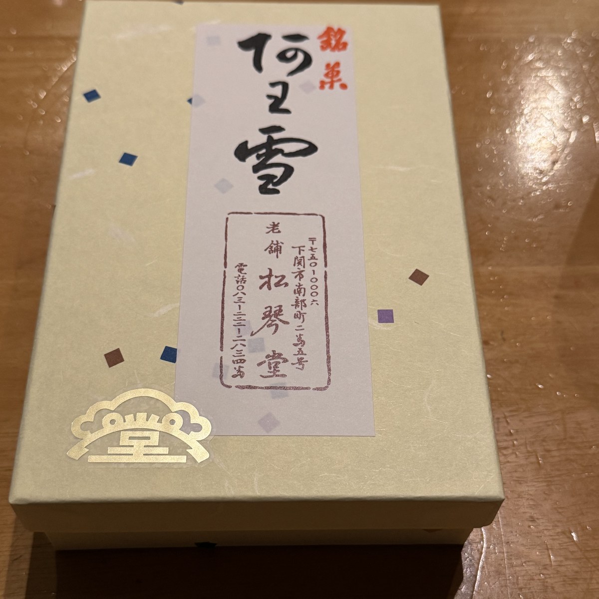 銘菓 阿わ雪の化粧箱。白い和紙の箱に「銘菓 阿わ雪 老舗 松琴堂」のラベルと金色の堂のマーク